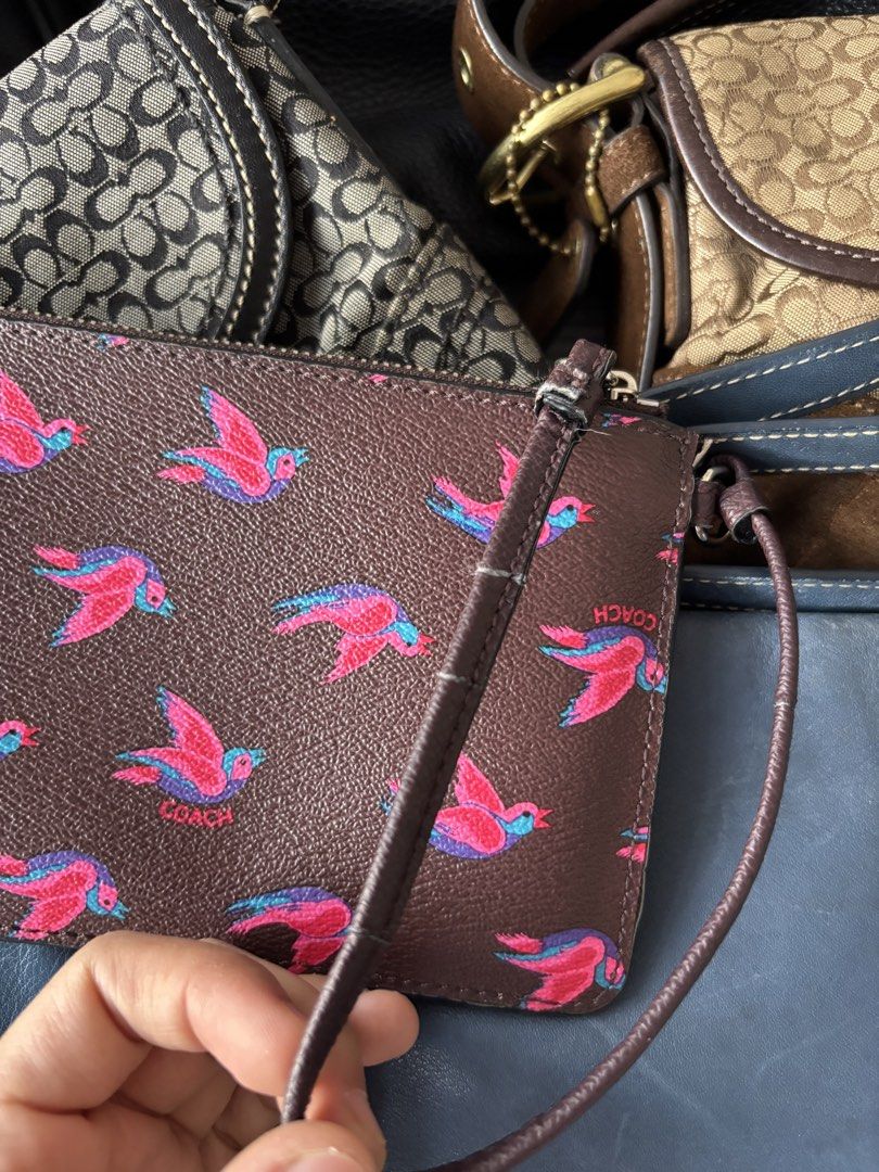 Coach Brown Bird Print Wristlet Pouch with Strap (Category: Purses & Pouches) located in Manila. Submitted by mpt99876 (Listing ID 1440994151, Image 3). Description: - Cute Coach wristlet pouch - Color: Brown with fun pink and blue bird print - Features a zippered closure - Interior card slots for organization - Includes care instructions and authenticity card - Ideal for keeping your essentials handy.