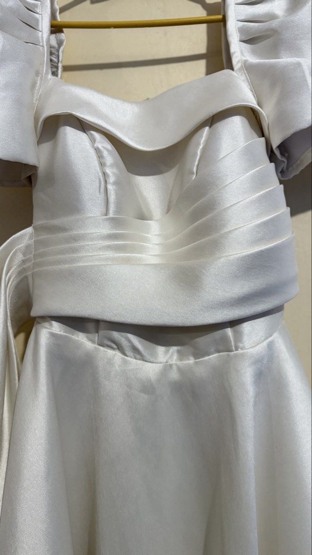 For rent Modern Filipiniana (Category: Dresses) located in Manila. Submitted by hello_lilies (Listing ID 1441017374, Image 3). Description: - Chic white dress - Features puff sleeves and a flattering square neckline - Cinched waist with elegant pleating - Adorned with a large bow detail on the side - Flowy A-line skirt for a graceful silhouette - Convenient back zipper closure - Ideal for parties, weddings, or any formal occasion.