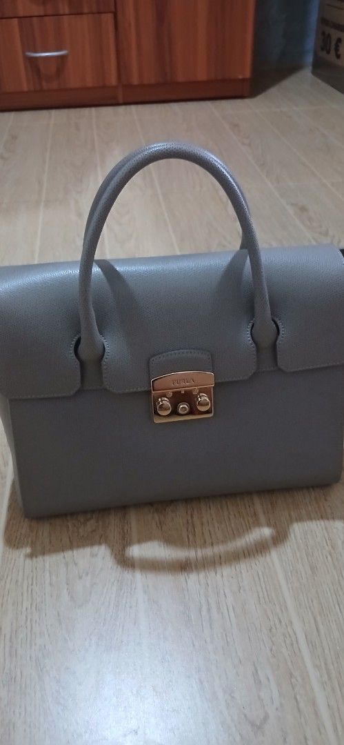 Furla Metropolis Bag Grey Leather (Category: Luxury Bags & Wallets) located in Rizal. Submitted by prelovedbymarlyn (Listing ID 1441032157, Image 1). Description: - Genuine grey leather Furla handbag - Elegant gold turn-lock closure with Furla logo - Comfortable top handles - Classic structured shape - Spacious interior with multiple compartments - used once with original tags attached bought in Europe - Versatile for daily use or special events.