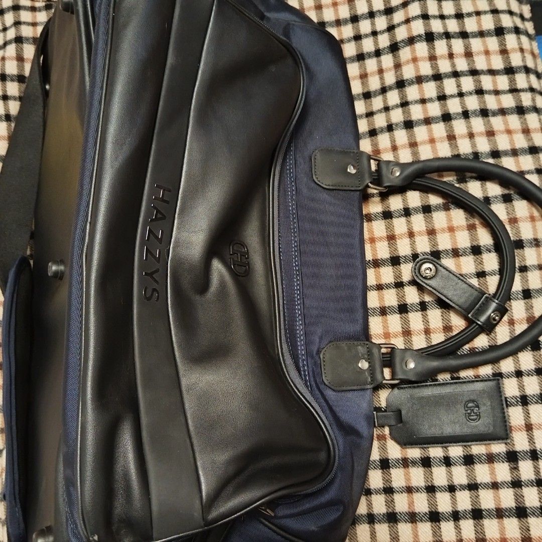 Hazzys Duffle Travel Bag (Category: Luxury Bags & Wallets) located in Bulacan. Submitted by brandedbagspreloved (Listing ID 1441041350, Image 1). Description: - Navy blue Hazzys duffel bag - Black leather trim and handles - Detachable shoulder strap - Multiple Hazzys logos (zipper pulls, luggage tag) - Spacious interior - Ideal for travel or gym -Large to XL lp posted no more huggling pls looks brandnew parang hindi ginamit.
