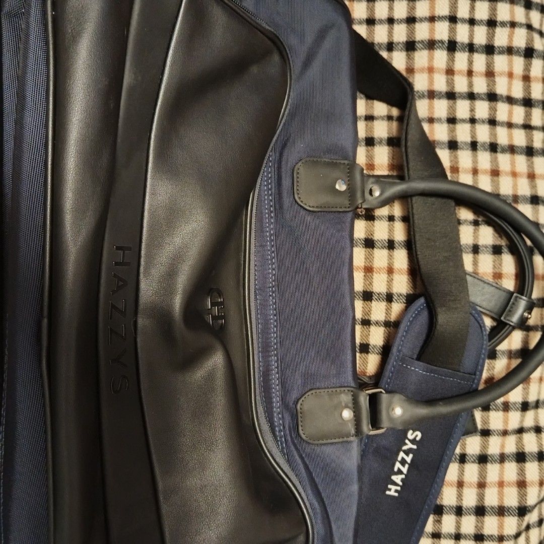 Hazzys Duffle Travel Bag (Category: Luxury Bags & Wallets) located in Bulacan. Submitted by brandedbagspreloved (Listing ID 1441041350, Image 2). Description: - Navy blue Hazzys duffel bag - Black leather trim and handles - Detachable shoulder strap - Multiple Hazzys logos (zipper pulls, luggage tag) - Spacious interior - Ideal for travel or gym -Large to XL lp posted no more huggling pls looks brandnew parang hindi ginamit.