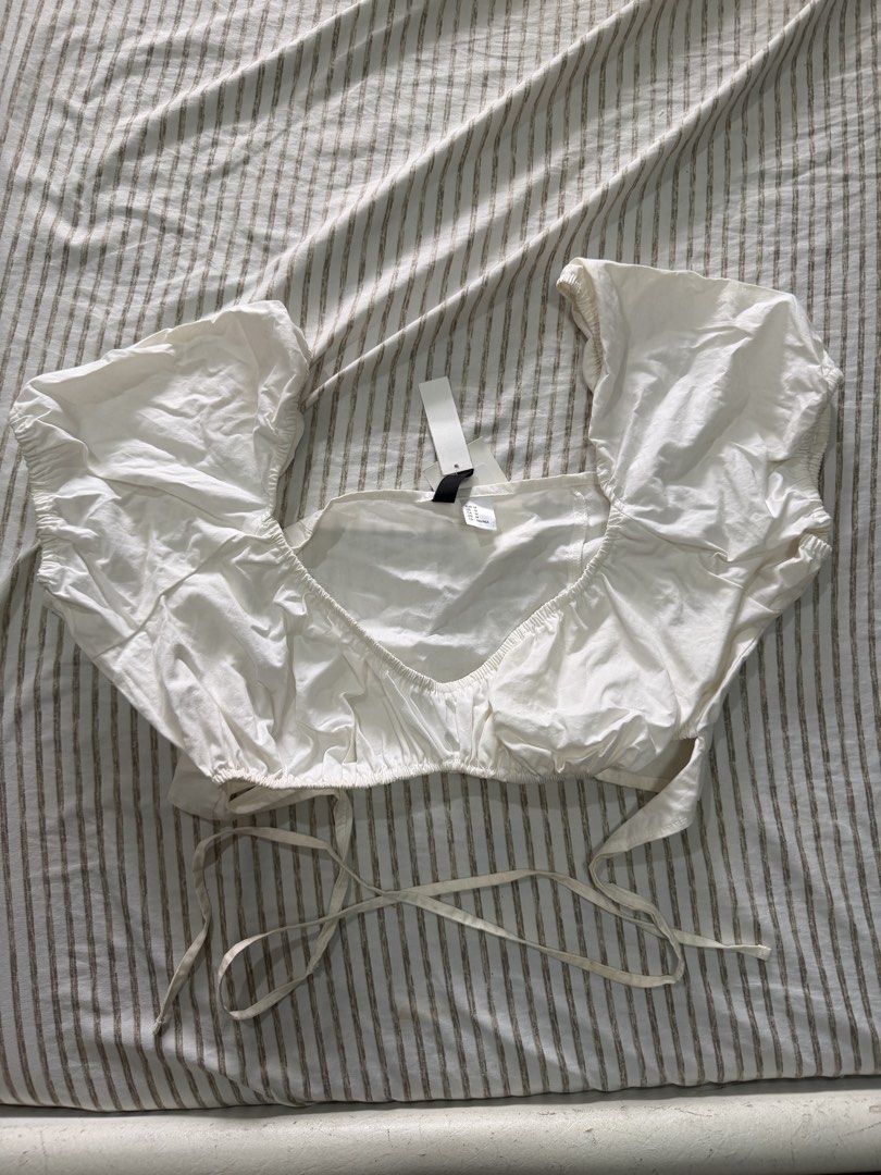 H&M White Puff Sleeve Tie Front Crop Top (Category: Blouses) located in Manila. Submitted by mento.ph (Listing ID 1441040538, Image 1). Description: - White puff sleeve crop top from H&M - Square neckline with tie front detail - Size: Medium (M) - Brand new with original tag attached.