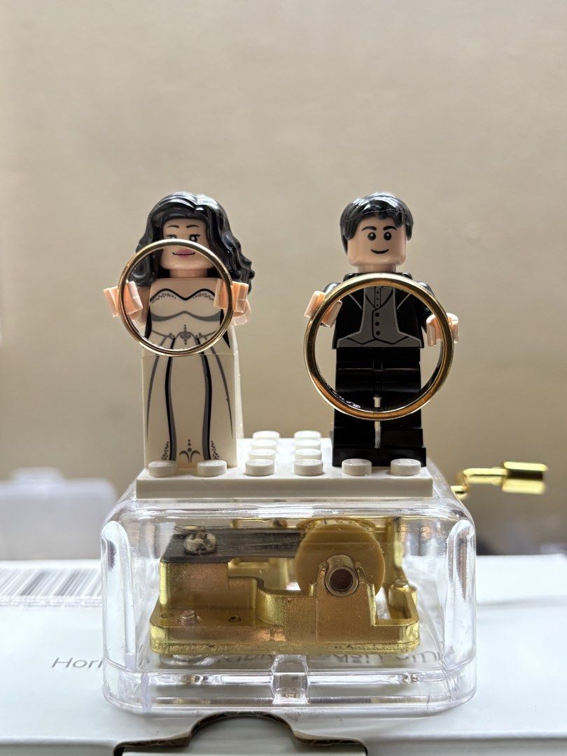 Lego Wedding Ring holder with Music Box (Category: Lego & Building Sets) located in Santa Rosa. Submitted by malyaolivera (Listing ID 1441155968, Image 3). Description: - Adorable Lego music box featuring a bride and groom. - Bride in white gown, groom in tuxedo. - They hold wedding rings. - Visible, gold-colored music box mechanism. - Turn the crank to play music. - Ideal for wedding gifts or Lego enthusiasts. Used for the wedding photos only.