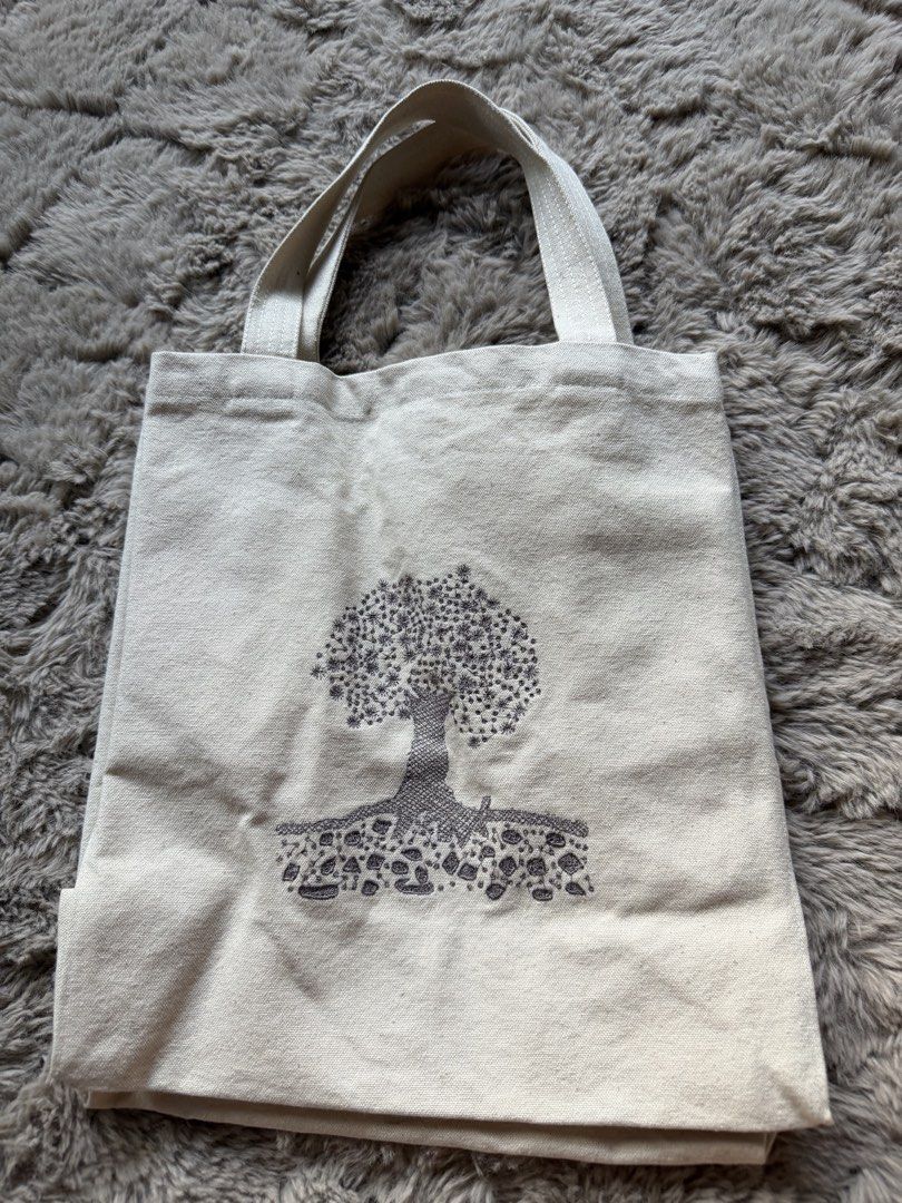 Santorini Canvas Tote Bag with Tree Design (Category: Tote Bags) located in Singapore. Submitted by franklinek (Listing ID 1441007417, Image 1). Description: - Authentic Santorini canvas tote bag - Natural beige color - Features a cute tree and roots graphic - Interior with small pockets - Sturdy handles for durability - Ideal for everyday use, shopping, or carrying books - Simple and practical design.