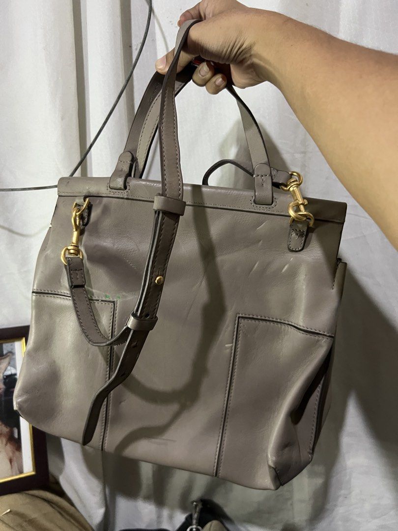 Tory Burch Grey Leather Tote Bag (Category: Luxury Bags & Wallets) located in Manila. Submitted by mightylion-ce6ea7 (Listing ID 1440968374, Image 2). Description: - Grey leather Tory Burch tote bag - Top handles and detachable shoulder strap - Magnetic snap closure on flap - Interior zippered compartment - Gold hardware - Note: Some scuffs and marks on the leather.