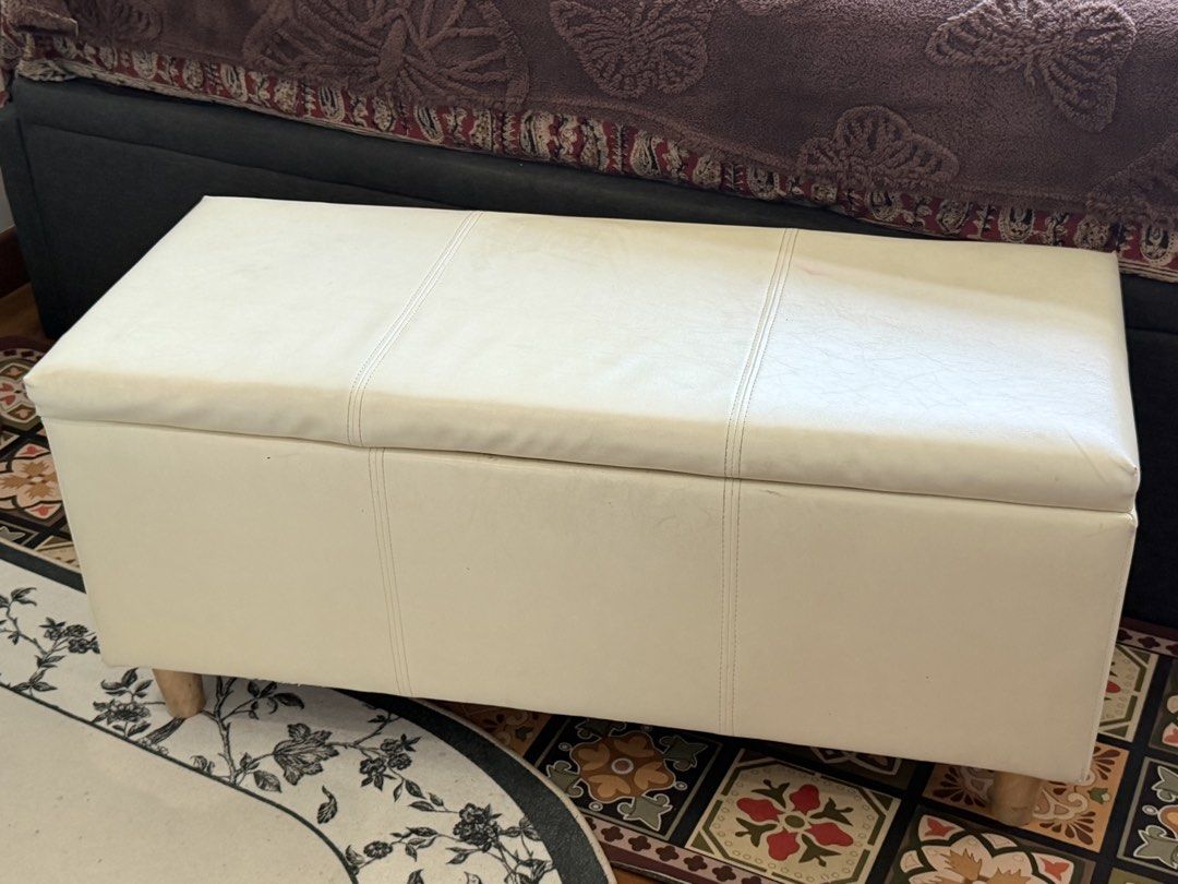 White Faux Leather Storage Ottoman Bench with Wooden Legs (Category: Chairs) located in Singapore. Submitted by priyanka_chatz (Listing ID 1441049454, Image 1). Description: - White faux leather storage ottoman - Hinged lid for easy access to storage - Minor exterior marks and a small pink stain (as pictured) - Lined interior - Stable wooden legs - Versatile for extra seating or storage in any room L - 99 cm B - 39 cm H - 45 cm.