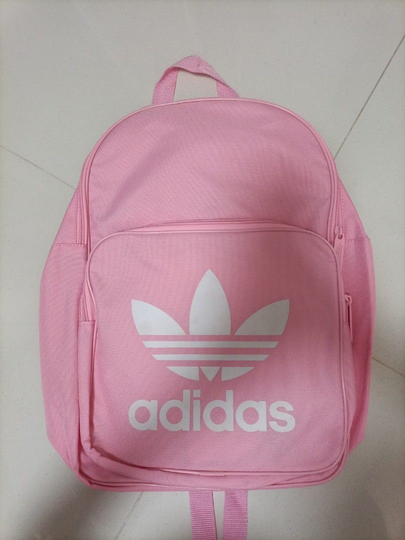 Authentic Adidas Pink Backpack (Category: Backpacks) located in Singapore. Submitted by iris_rae (Listing ID 1436046120, Image 1). Description: - Pink Adidas backpack - Features the Adidas trefoil logo - Adjustable shoulder straps - Top handle - Suitable for everyday use - Minor yellowing marks on logo comes with free pink doraemon bag charm Abit of yellowing on the doraemon.