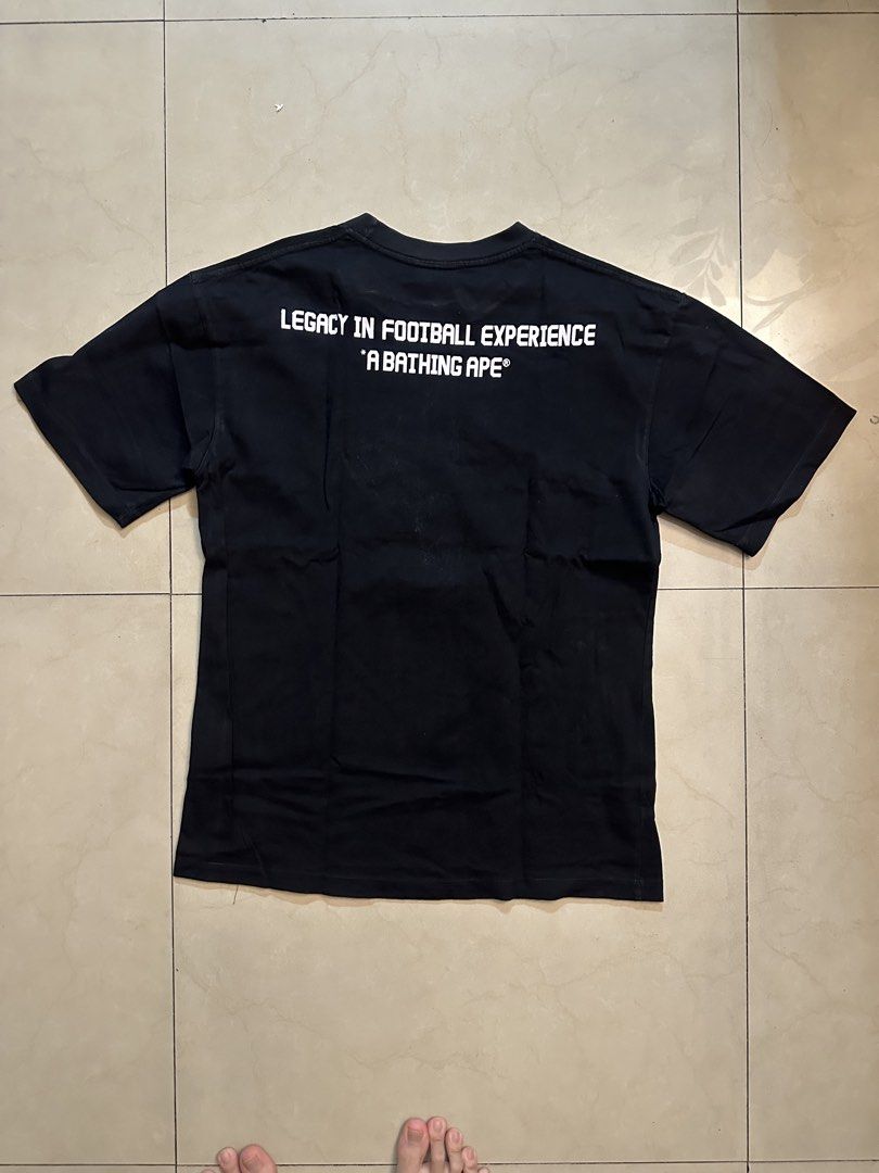BAPE CR7 Life T-shirt (Category: Tshirts & Polo Shirts ) located in Manila. Submitted by almightyvinson (Listing ID 1435982529, Image 2). Description: - Black BAPE T-shirt - Features a camouflage Ape Head graphic on the front - Front print: "CR7 LIFE" and "A BATHING APE" - Back print: "LEGACY IN FOOTBALL EXPERIENCE" and "A BATHING APE".
