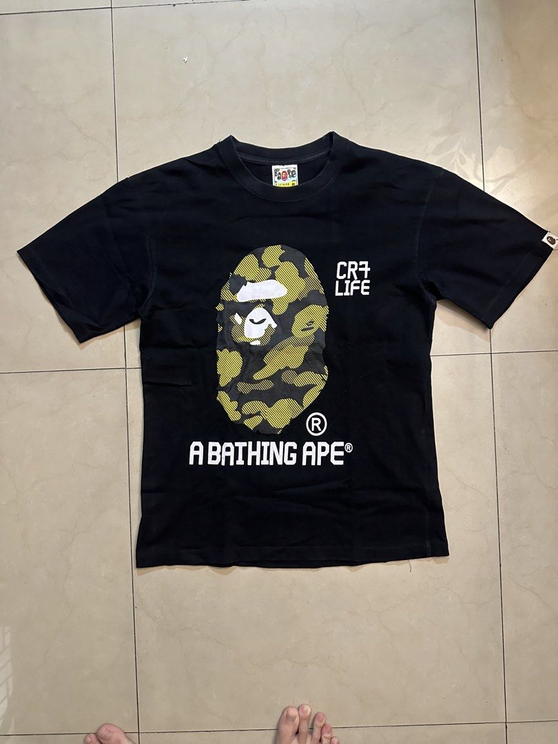 BAPE CR7 Life T-shirt (Category: Tshirts & Polo Shirts ) located in Manila. Submitted by almightyvinson (Listing ID 1435982529, Image 1). Description: - Black BAPE T-shirt - Features a camouflage Ape Head graphic on the front - Front print: "CR7 LIFE" and "A BATHING APE" - Back print: "LEGACY IN FOOTBALL EXPERIENCE" and "A BATHING APE".