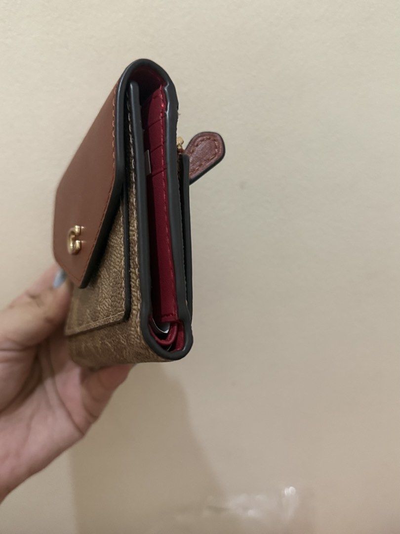 Coach Signature Small Wallet (Category: Luxury Bags & Wallets) located in Quezon City. Submitted by msaisa (Listing ID 1435952904, Image 3). Description: - Authentic Coach wallet - Signature C design - Brown and tan exterior - Red interior - Multiple card slots - Coin compartment - Includes original tags.