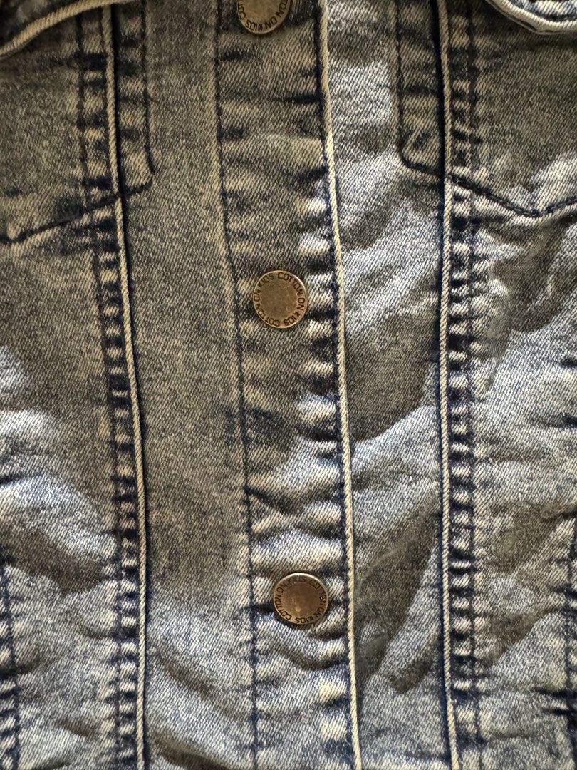 Cotton On Kids Denim Jacket (Category: Babies & Kids Fashion) located in Quezon City. Submitted by Tasi671 (Listing ID 1435997866, Image 2). Description: - Cotton On Kids denim jacket - Size: 5-6 - Light blue wash look (vintage look) - Classic design with button closures and pockets - Made in Bangladesh - Versatile for various outfits - Suitable for everyday wear SRP 2,500.