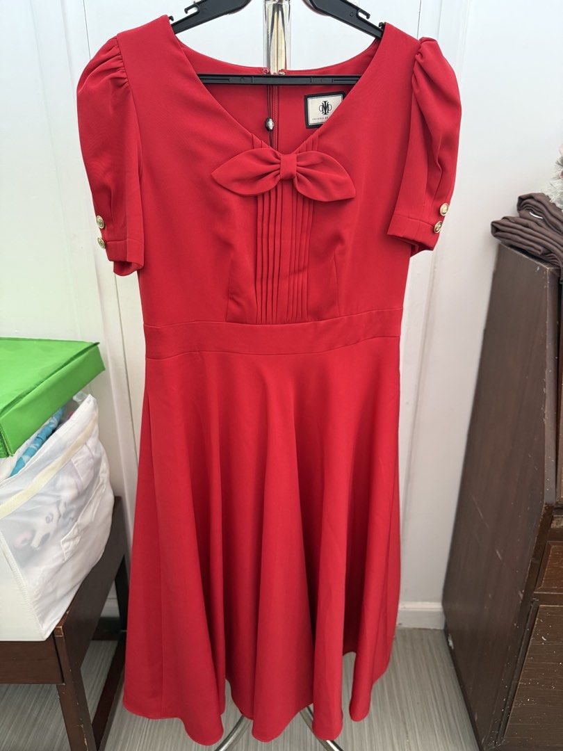 Insignia de Manila Red Dress (Category: Dresses) located in Quezon City. Submitted by reivia.vend (Listing ID 1435954192, Image 2). Description: - Brand new red dress from Insignia de Manila - Features a stylish bow detail at the neckline - Pleating on the bodice adds a touch of elegance - Short sleeves with chic gold button accents - Designed with a fitted waist for a flattering silhouette - Flared skirt for a graceful look - Comes with original