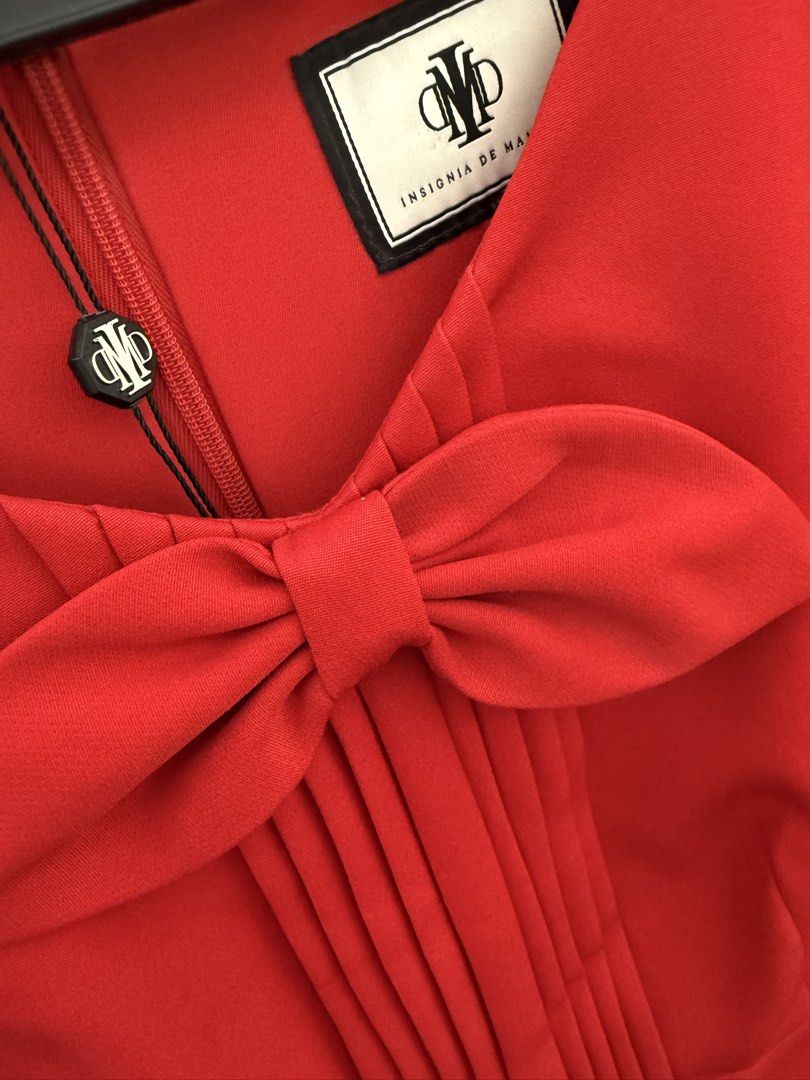 Insignia de Manila Red Dress (Category: Dresses) located in Quezon City. Submitted by reivia.vend (Listing ID 1435954192, Image 3). Description: - Brand new red dress from Insignia de Manila - Features a stylish bow detail at the neckline - Pleating on the bodice adds a touch of elegance - Short sleeves with chic gold button accents - Designed with a fitted waist for a flattering silhouette - Flared skirt for a graceful look - Comes with original