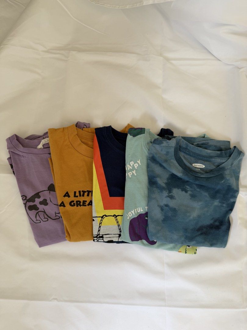 Kids' Graphic T-shirts Bundle 5-6 (Category: Babies & Kids Fashion) located in Marilao. Submitted by mebslerman (Listing ID 1435986274, Image 1). Description: - 5-piece set of kids' graphic t-shirts - Includes: - Purple shirt with pig design - Orange shirt with text - Navy shirt with colorful design - Light blue shirt with text - Tie-dye blue shirt - All shirts are short-sleeved..