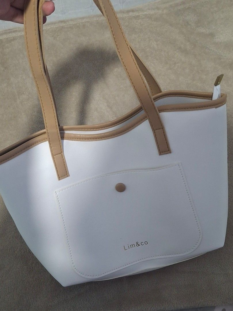 Lim & Co White Tote Bag (Category: Tote Bags) located in Plaridel. Submitted by niannyyy (Listing ID 1435991364, Image 2). Description: - White tote bag from Lim & Co. - Front pocket with button closure. - Tan-colored handles and trim. - Zipper closure at the top. - Made of smooth material. - Lim & Co logo on front..