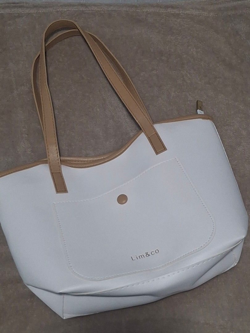 Lim & Co White Tote Bag (Category: Tote Bags) located in Plaridel. Submitted by niannyyy (Listing ID 1435991364, Image 1). Description: - White tote bag from Lim & Co. - Front pocket with button closure. - Tan-colored handles and trim. - Zipper closure at the top. - Made of smooth material. - Lim & Co logo on front..