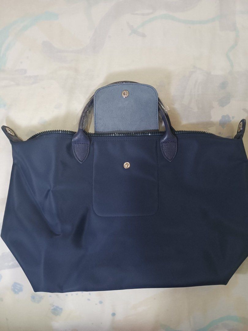 Authentic Longchamp Le Pliage Néo tote bag (Category: Luxury Bags & Wallets) located in San Juan City. Submitted by rctdeclutter_ (Listing ID 1435976347, Image 2). Description: * Features a textured leather flap with an embossed logo snap button. * Constructed from durable nylon and includes a removable shoulder strap. * The bag is designed to be lightweight and foldable for convenience * Brand new in excellent condition * Snap Button and Zipper 