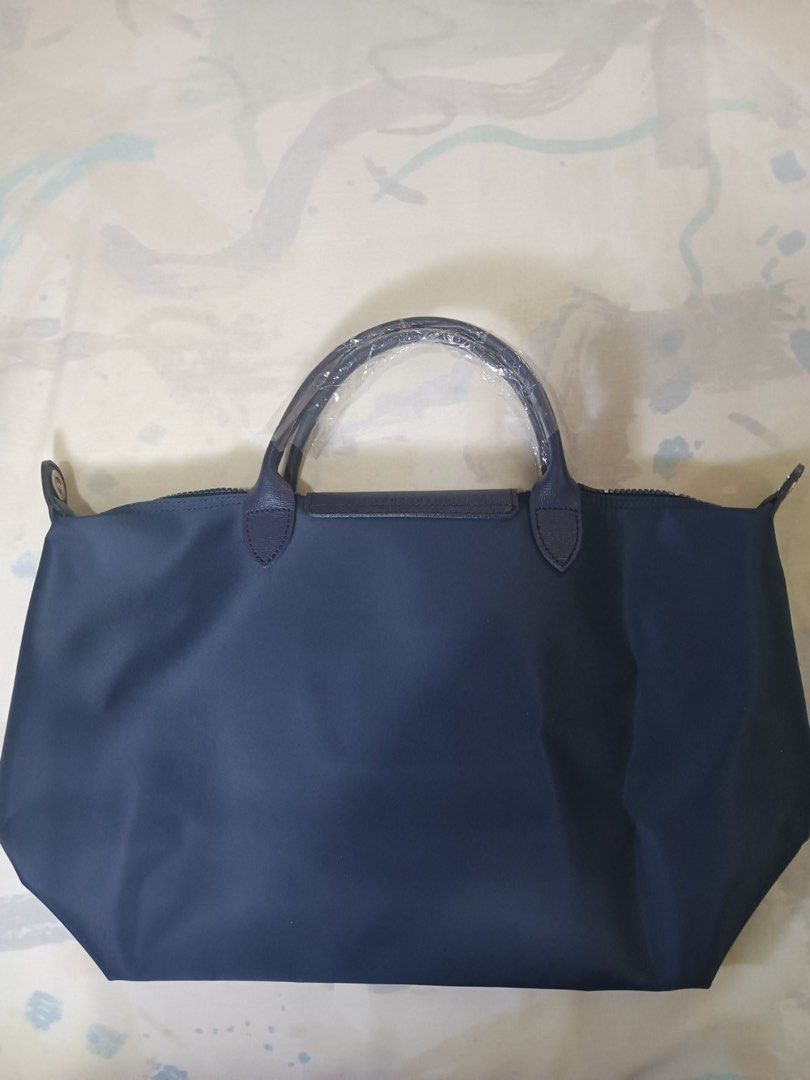 Authentic Longchamp Le Pliage Néo tote bag (Category: Luxury Bags & Wallets) located in San Juan City. Submitted by rctdeclutter_ (Listing ID 1435976347, Image 3). Description: * Features a textured leather flap with an embossed logo snap button. * Constructed from durable nylon and includes a removable shoulder strap. * The bag is designed to be lightweight and foldable for convenience * Brand new in excellent condition * Snap Button and Zipper 