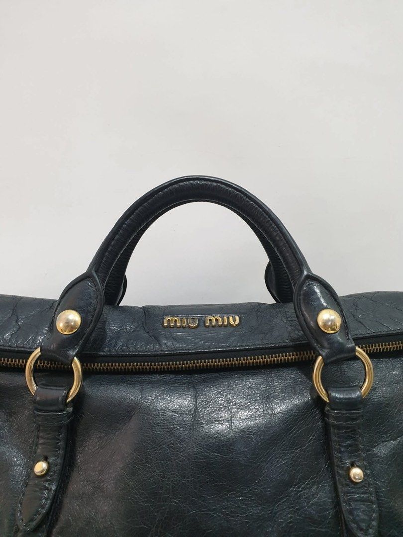 Miu Miu Vitello Lux Leather Bow Bag (Category: Luxury Bags & Wallets) located in Manila. Submitted by na.serr (Listing ID 1435970323, Image 3). Description: - Miu Miu black leather handbag - Top handle and detachable shoulder strap - Gold-tone hardware - Zip closure - Textured leather finish - Brand name visible on front.