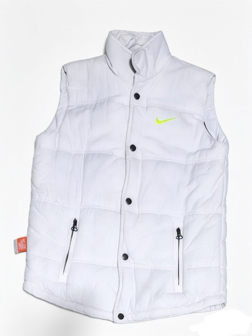 Nike Puffer Vest (Category: Vests) located in Bulacan. Submitted by rb_smn (Listing ID 1436051233, Image 1). Description: - White Nike puffer vest - Neon green Nike logo - High collar - Button and zipper closure - Two front pockets - Blue interior lining - Nike tag with product info - 100% cotton.