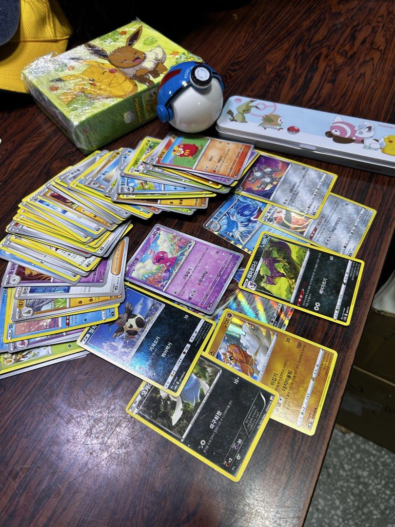 Pokemon Trading Cards Bundle (Category: Toys & Games) located in Manila. Submitted by starbalesukandjapansurplus (Listing ID 1435987969, Image 1). Description: - Pokemon trading card bundle - Includes cards with Korean text - Comes with a Pokemon-themed box - Includes a Poke Ball - Includes a pencil case - Features cards from various sets - Great for collectors and players.