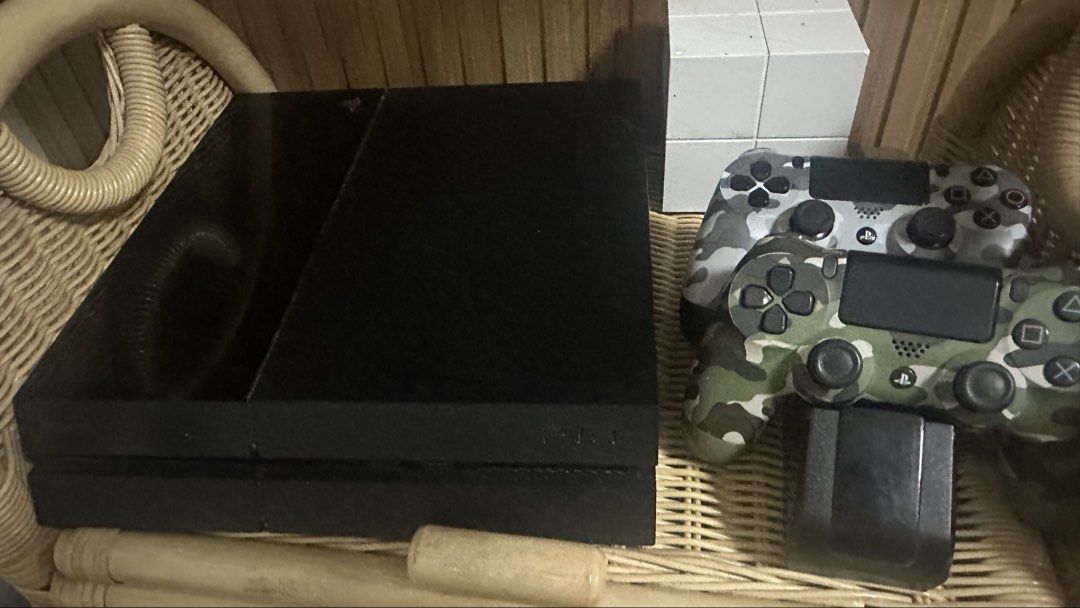 Sony PlayStation 4 Console with Controllers (Category: PlayStation) located in Cavite. Submitted by eychteee (Listing ID 1436022801, Image 2). Description: Includes a black Sony PlayStation 4 console and two camouflage controllers. Also comes with a charging dock for the controllers. The controllers have a unique camouflage design. The console and controllers are shown together in the images. Bought in the us.