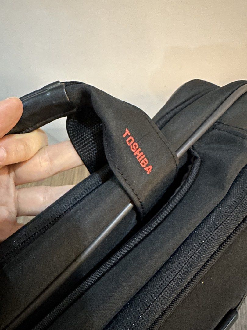 Toshiba Laptop Bag with Shoulder Strap (Category: Laptop Bags & Sleeves) located in Caloocan City. Submitted by kween.of.decluttering (Listing ID 1436078582, Image 2). Description: - Black Toshiba laptop bag - Features a handle and detachable shoulder strap - Multiple internal compartments - Includes pockets for pens and accessories - Toshiba logo on front and handle strap - Comes with a lifetime warranty.