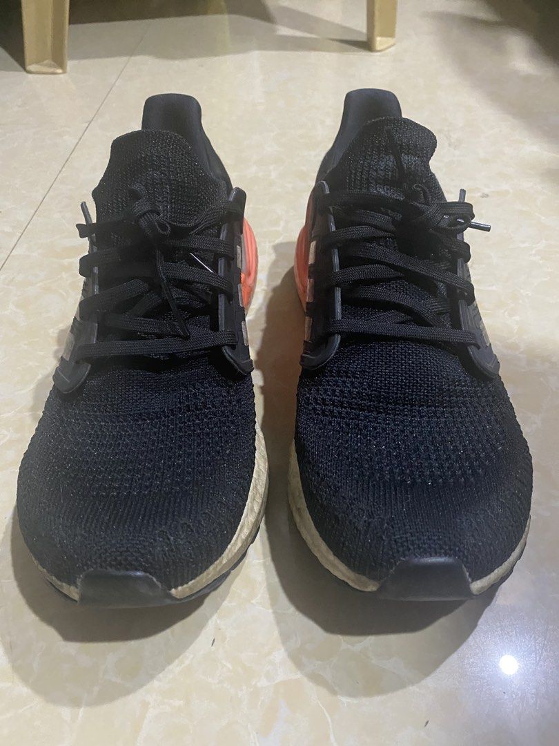 Adidas Ultraboost 20 Black Orange (Category: Sneakers) located in Manila. Submitted by decluttering_007 (Listing ID 1436101807, Image 1). Description: Negotiable Signs of use, intact. Ready to use Adidas Ultraboost 20 sneakers in black with orange accents. Features the iconic three stripes on the sides. The soles show some wear. The shoes have black laces and a breathable knit upper. The heel counter is orange. The boost midsole is visible..