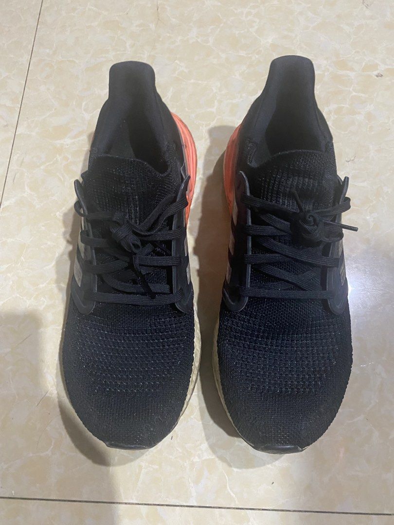 Adidas Ultraboost 20 Black Orange (Category: Sneakers) located in Manila. Submitted by decluttering_007 (Listing ID 1436101807, Image 2). Description: Negotiable Signs of use, intact. Ready to use Adidas Ultraboost 20 sneakers in black with orange accents. Features the iconic three stripes on the sides. The soles show some wear. The shoes have black laces and a breathable knit upper. The heel counter is orange. The boost midsole is visible..