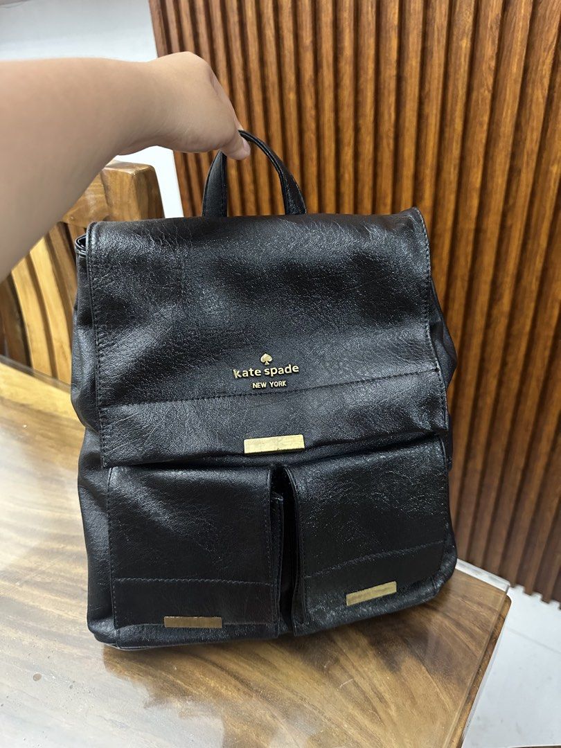Kate Spade New York Black Backpack Convertible (Category: Backpacks) located in Batangas. Submitted by jhinp0t (Listing ID 1436231316, Image 1). Description: Genuine Leather Black Kate Spade backpack with two front pockets. Features a top handle and adjustable shoulder straps. The interior has a Kate Spade label and a zipper pocket. The zipper pull has the Kate Spade logo. The backpack has gold-tone hardware. Issue: This is my project bag brought