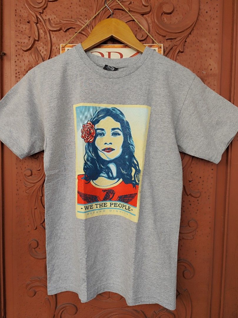 Obey We The People Graphic Tee (Category: Tshirts & Polo Shirts ) located in Pasig City. Submitted by keilahsmom (Listing ID 1436236363, Image 1). Description: Dimes: L26 W17 1/2 Size on tag: S Color rate: 10/10 Condition: Excellent 10/10 Issue(s): none Buong buo ang print walang crack or any hair line. Grey Obey t-shirt features a graphic print on the front with the words "We The People" and a portrait of a woman with a rose. The back of the shi
