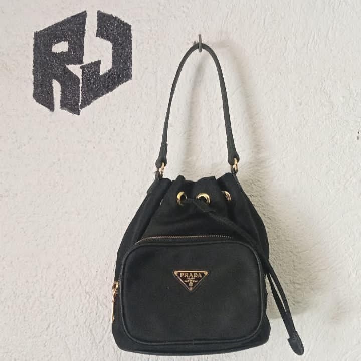 Prada Drawstring Bucket Bag (Category: Luxury Bags & Wallets) located in Manila. Submitted by kuyanyo (Listing ID 1436205786, Image 1). Description: - Authentic Prada bucket bag - Black nylon material - Gold-tone hardware - Front zippered pocket with Prada logo - Drawstring closure - Top handle - Prada logo on zipper DM IF INTIRESTED EXCELLENT CONDITION NEEDWASH.