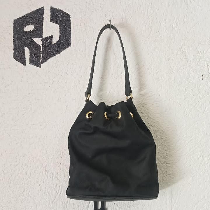 Prada Drawstring Bucket Bag (Category: Luxury Bags & Wallets) located in Manila. Submitted by kuyanyo (Listing ID 1436205786, Image 2). Description: - Authentic Prada bucket bag - Black nylon material - Gold-tone hardware - Front zippered pocket with Prada logo - Drawstring closure - Top handle - Prada logo on zipper DM IF INTIRESTED EXCELLENT CONDITION NEEDWASH.