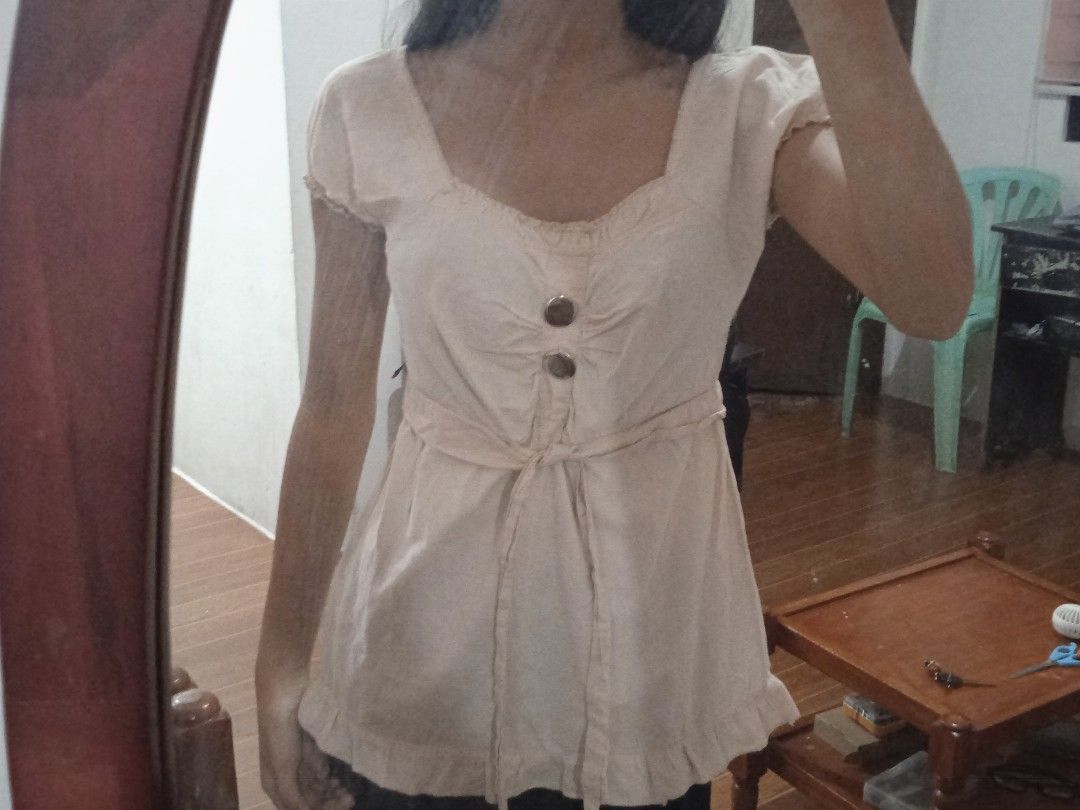 Dolly Top (Category: Blouses) located in Manila. Submitted by ariaclothing.3030 (Listing ID 1436443291, Image 2). Description: -Dolly vintage top - Short sleeves - Tie waist for adjustable fit - Subtle ruffle hem detail - Light, neutral color - Two front buttons - Lightweight, breathable fabric.