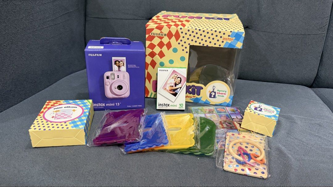 Fujifilm Instax Mini 13 Candy Pink Fun Kit (Category: Cameras) located in Quezon City. Submitted by ladyowned (Listing ID 1436326066, Image 2). Description: Bundle includes a Fujifilm Instax Mini 13 camera in Candy Pink, a Fun Kit box, and other accessories. The Fun Kit box contains a variety of items, including film, a mini album, and decorative accessories. Also included is a tote bag with a shoulder strap..