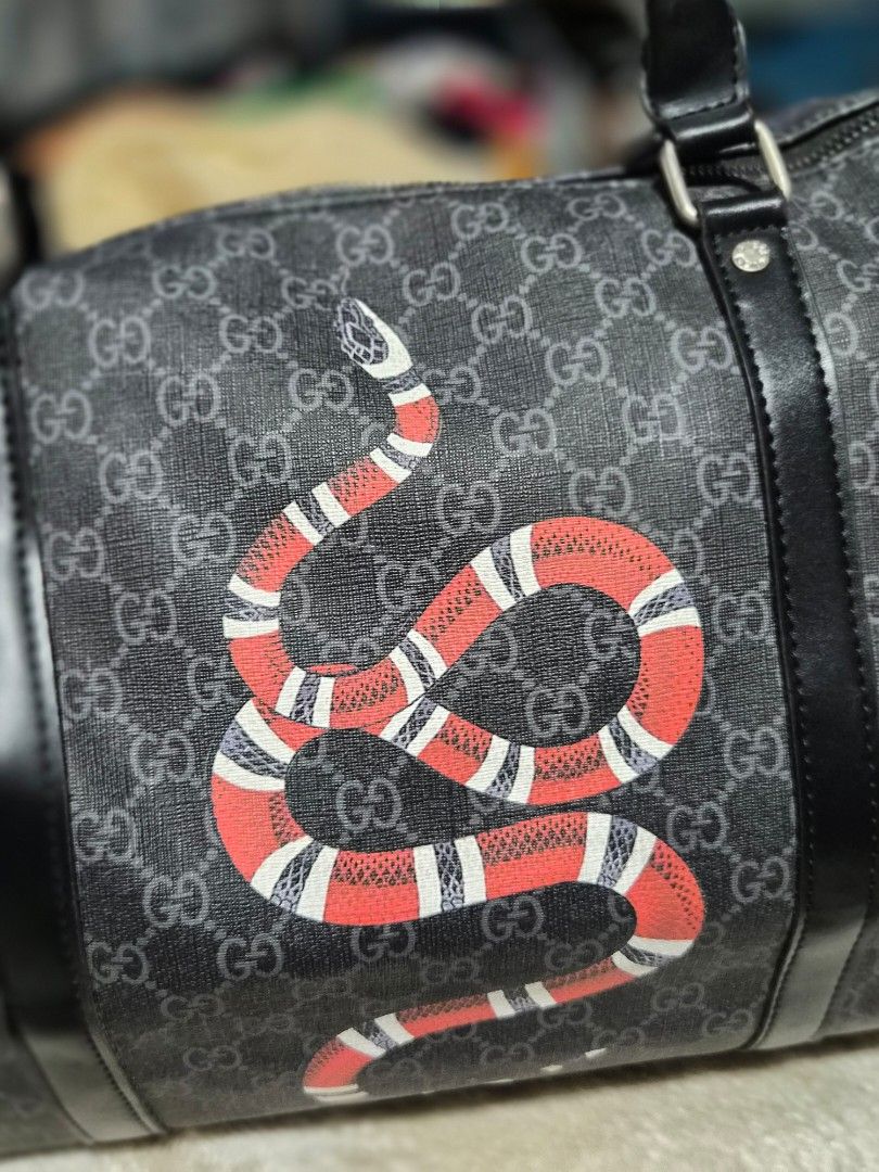 Gucci Snake Print Duffle Bag (Category: Chilled & Frozen Food) located in Mandaue City. Submitted by chuchi152615 (Listing ID 1436325742, Image 2). Description: Gucci duffle bag features a striking snake print design. It has a top handle and a detachable shoulder strap for versatile carrying options. The bag includes a main compartment with a zipper closure and an interior pocket. The bag is adorned with the iconic Gucci logo pattern. The strap h