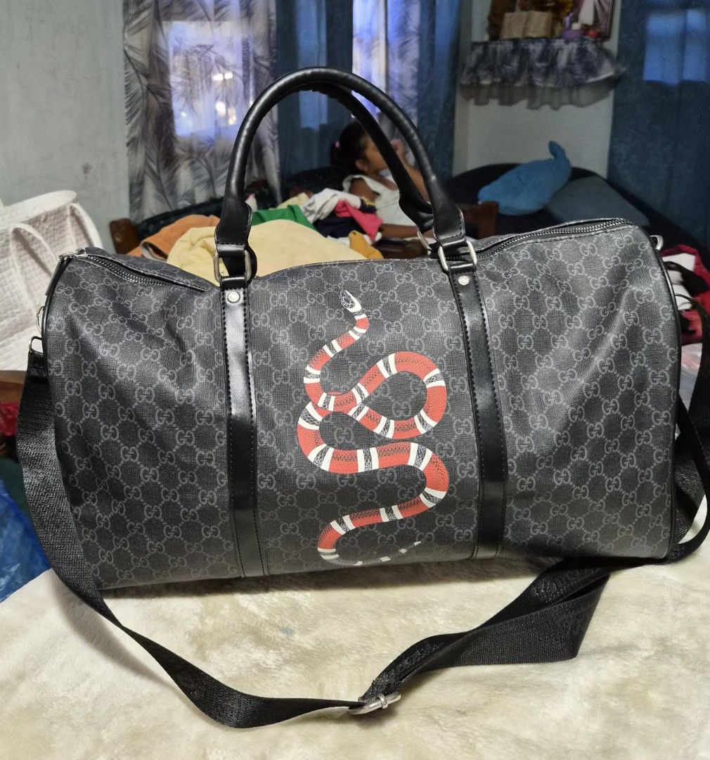 Gucci Snake Print Duffle Bag (Category: Chilled & Frozen Food) located in Mandaue City. Submitted by chuchi152615 (Listing ID 1436325742, Image 1). Description: Gucci duffle bag features a striking snake print design. It has a top handle and a detachable shoulder strap for versatile carrying options. The bag includes a main compartment with a zipper closure and an interior pocket. The bag is adorned with the iconic Gucci logo pattern. The strap h