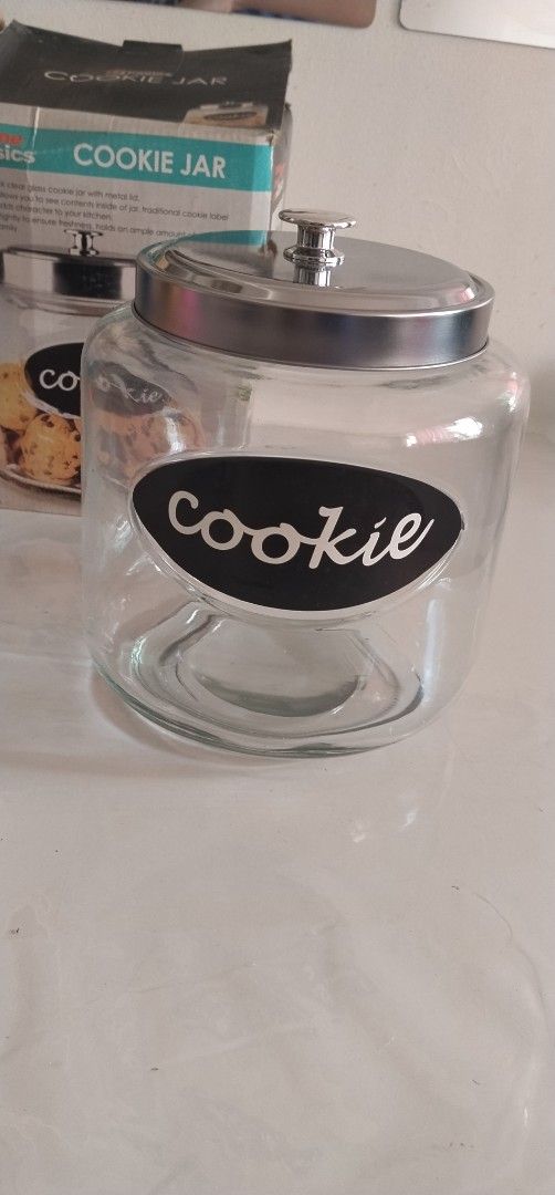 Home Basics Cookie Jar with Metal Lid (Category: Food Organization & Storage) located in Pasig City. Submitted by magsajokat46354 (Listing ID 1436299231, Image 1). Description: - Home Basics cookie jar - Clear glass design - Metal lid - Features a "Cookie" label - Heavy-duty, thick glass - never used with original box.