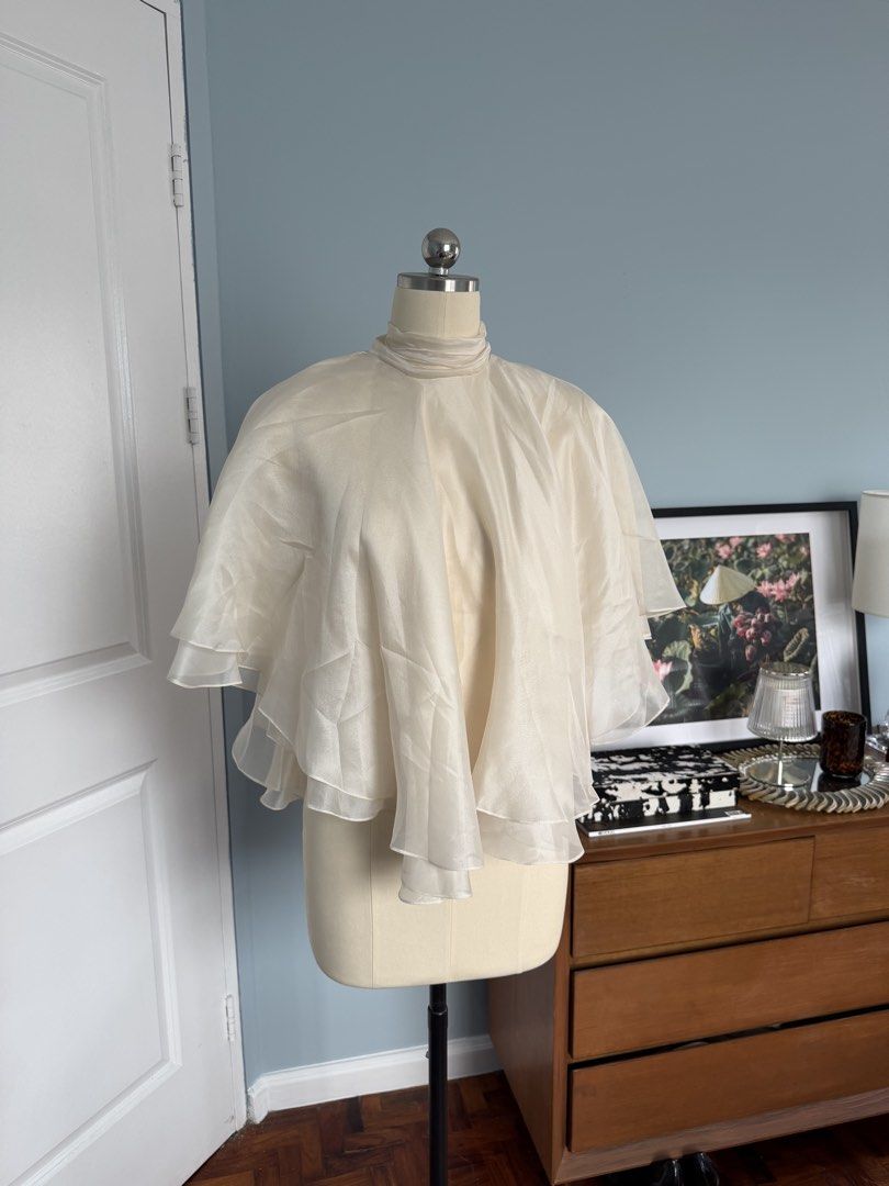 Huong Boutique Kieu Silk Blouse (Category: Blouses) located in Quezon City. Submitted by ladybd (Listing ID 1436369403, Image 3). Description: - Huong Boutique silk blouse - Size: S - Color: Off-white - Design: Cape with layered ruffles - Features: High neck, tie back - Ideal for: Special occasions or everyday wear.