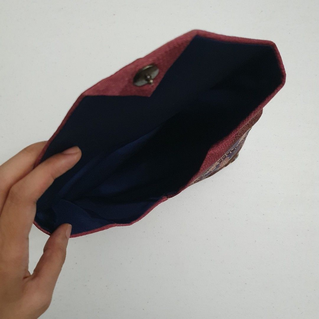 Japanese Fabric Clutch (Category: Clutches) located in Paranaque City. Submitted by cobien (Listing ID 1436399237, Image 3). Description: - Japanese fabric design - Floral and geometric patterns - Colors: Purple, brown, and green - Dark blue interior - Flap closure with button - Size: Approximately 8.75 x 6.5 inches.