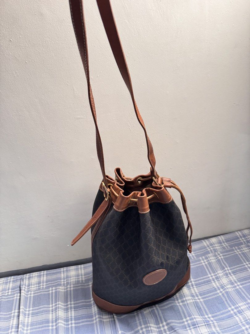 Longchamp Vintage Leather Bucket Bag (Category: Luxury Bags & Wallets) located in Rosales. Submitted by thriftingismygame (Listing ID 1436465424, Image 3). Description: - Vintage Longchamp bucket bag - Brown leather trim and strap - Drawstring closure - Crossbody strap - Brown patterned exterior - Leather logo patch - Gold-tone hardware.