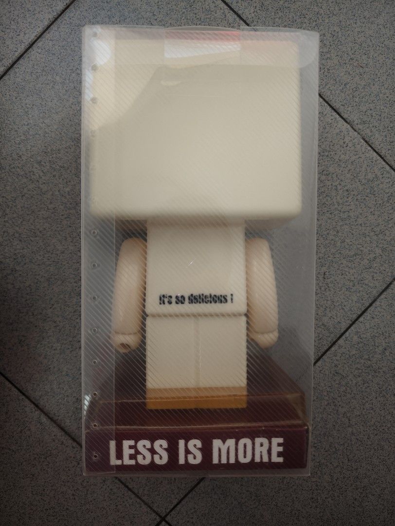Luck Bread Saving Box (Category: Designer & Blind Box Toys) located in Pantai Remis. Submitted by winkmei (Listing ID 1436340494, Image 2). Description: Luck Bread Saving Box. It features a cute bread-shaped head and a body with arms and legs. The box is in its original packaging. The base of the box has the words "LESS IS MORE" and "It's so delicious!". This is totally new since bought ya.
