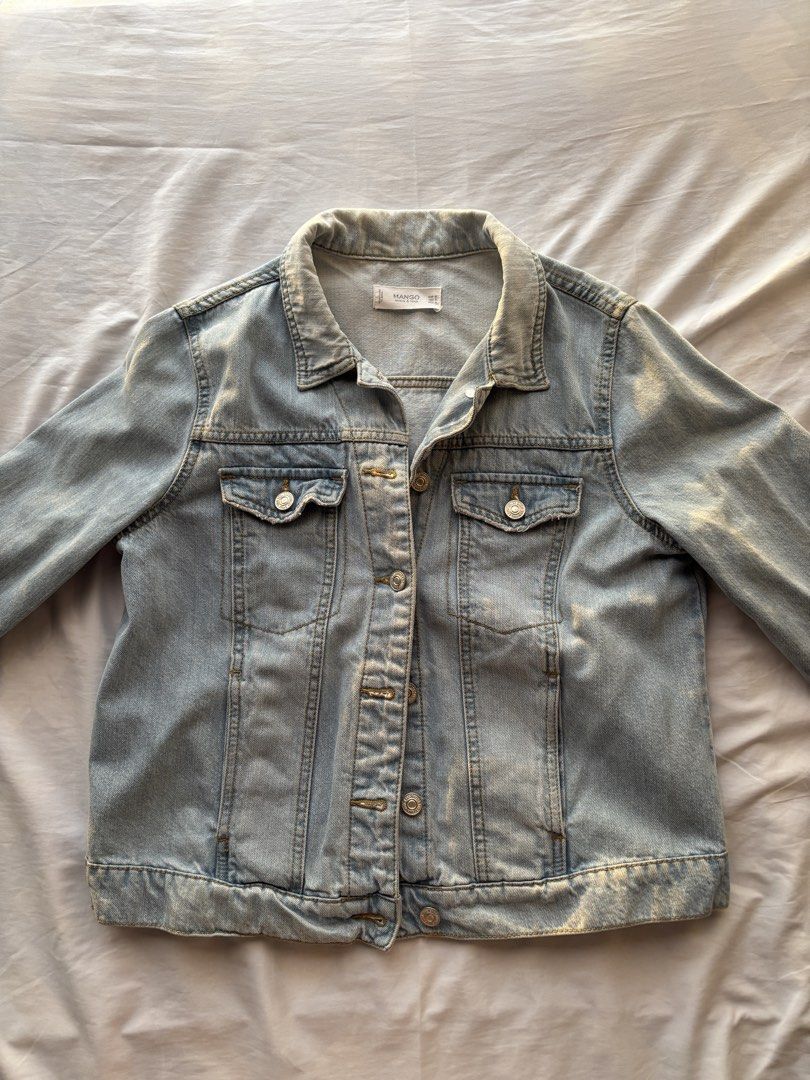 Mango Denim Jacket (Category: Coats, Jackets and Outerwear) located in Guiguinto. Submitted by drlsaldi (Listing ID 1436388263, Image 1). Description: - Light blue denim jacket from Mango - Classic button-down design - Features two chest pockets - Collared neckline - Buttoned cuffs - Mango label visible - Versatile for various outfits.