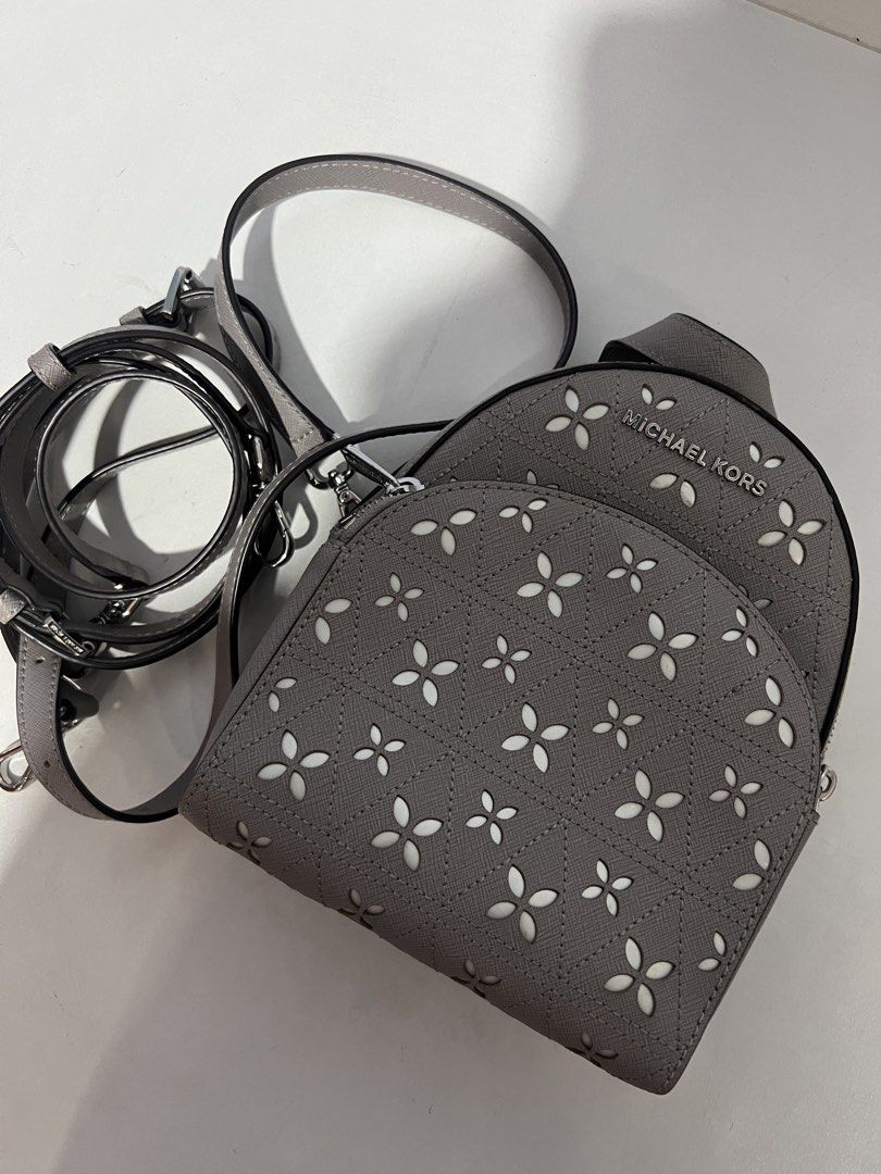 Michael Kors Convertible Backpack (Category: Luxury Bags & Wallets) located in Quezon City. Submitted by roseela (Listing ID 1436424711, Image 1). Description: - Michael Kors convertible bag - Gray exterior with floral cut-out design - Can be worn as a backpack or crossbody - Interior features a zippered pocket and Michael Kors logo lining - Includes detachable strap and top handle - Silver-tone hardware - MOP: GCASH/BDO - LOC: QC.