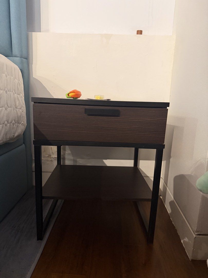 Bedside table (Category: Shelves, Cabinets & Racks) located in Singapore. Submitted by cnf1990713 (Listing ID 1436415145, Image 1). Description: - Stylish nightstand - Features a drawer and lower shelf - Dark brown wood-look finish - Black metal frame - Minimal wear - Pickup only L45cm W40cm H53cm .