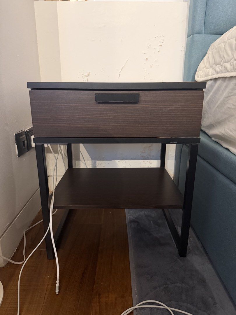 Bedside table (Category: Shelves, Cabinets & Racks) located in Singapore. Submitted by cnf1990713 (Listing ID 1436415145, Image 2). Description: - Stylish nightstand - Features a drawer and lower shelf - Dark brown wood-look finish - Black metal frame - Minimal wear - Pickup only L45cm W40cm H53cm .