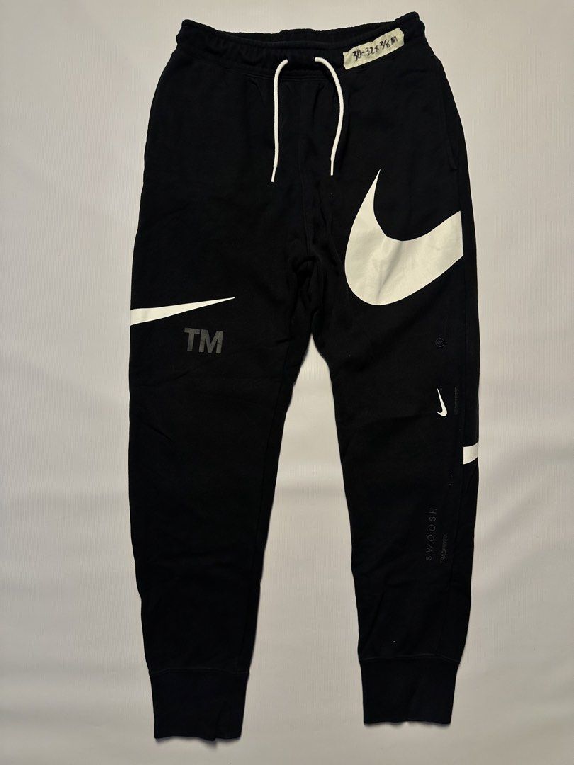 Nike Swoosh Sweatpants - Black - Size M (Category: Joggers) located in Manila. Submitted by johnedel_james (Listing ID 1436429791, Image 1). Description: Black Nike sweatpants with large white swoosh logos. Features a drawstring waist and elastic cuffs. The size is M. Made in China. The tag indicates the style code DD6092-010. The material composition is 80% cotton and 20% polyester. The waist size is indicated as 30-32.5 inches..