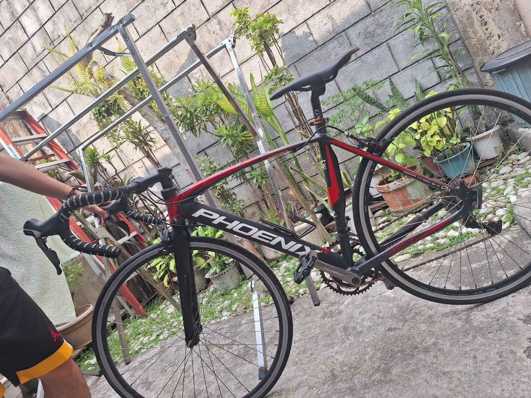 Phoenix Road Bike (Category: Bicycles) located in Caloocan City. Submitted by cee_empreloveditems (Listing ID 1436429532, Image 2). Description: Phoenix Speed Cross Pro Bike The PRICE STILL NEGOTIABLE, pwedeng pwede babaan, PM ME for more details. - Black and Red frame, Alluminum Alloy. - Has rusty on belt, flat tires and is heavily used, minor repair will work. - Free helmet. Reason for selling: wala na gumagamit kaya nakatambak nalang sa isang 