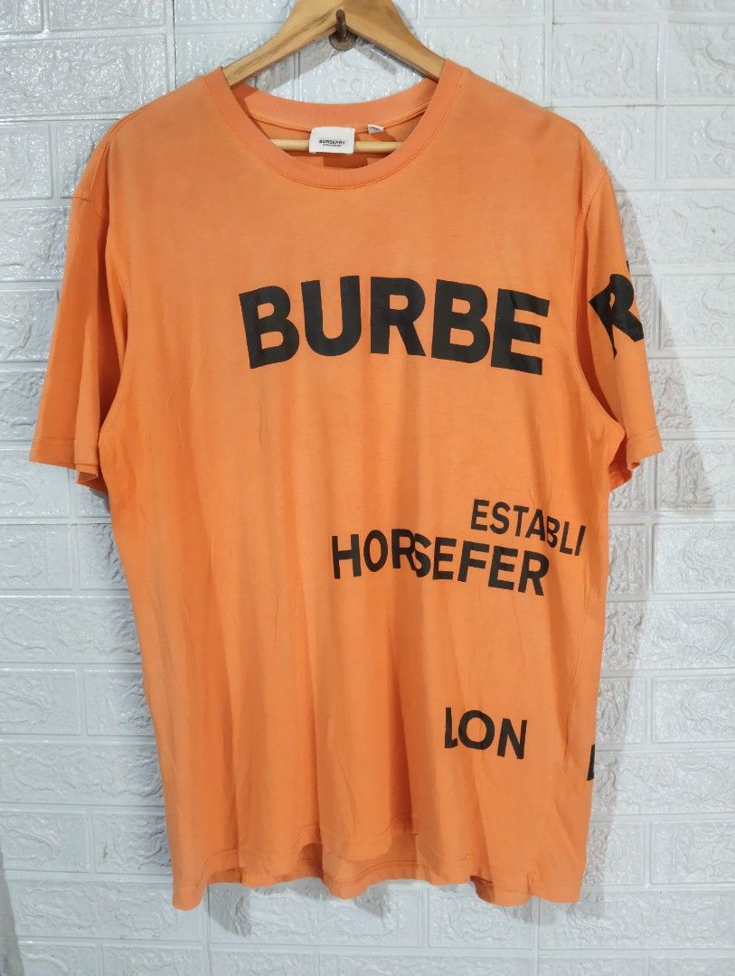 Burberry Orange Graphic Tee XXL (Category: Tshirts & Polo Shirts ) located in Davao. Submitted by noelamihan05424 (Listing ID 1436515880, Image 1). Description: - Authentic Burberry t-shirt - Color: Orange - Graphic Print: Black - Features: Brand name and "ESTABLI HORSEFER LON" text - Size: XXL - Dimes 23x30 - Made in: London, England - Neckline: Crew neck - Sleeves: Short sleeves - Includes Burberry logo tag - Issue cut wash tag minimal sign of 