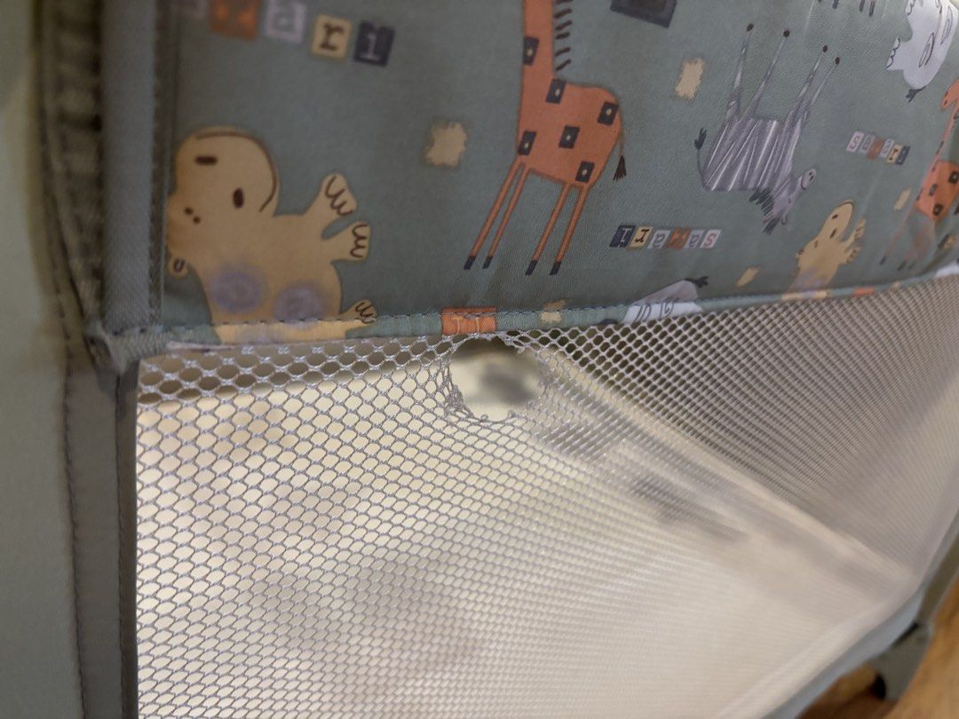 Graco Pack 'n Play Playard (Category: Cots & Cribs) located in Manila. Submitted by supersaleclub (Listing ID 1436650082, Image 3). Description: Graco Pack 'n Play playard features a playful animal print. It includes a mattress and a mobile with hanging toys. The playard has mesh sides for visibility and ventilation. There is a small hole in the mesh. The frame is a light green color..